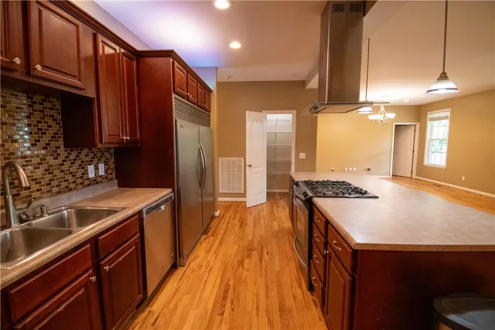 An inviting kitchen features a gas range on a central island and richly toned cabinetry.