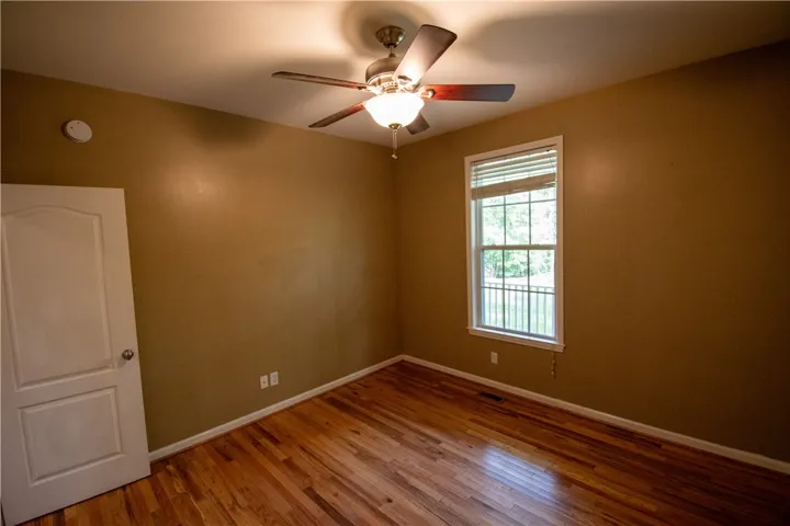 Hardwood floors and a bright window elevate this comfortable bedroom space.