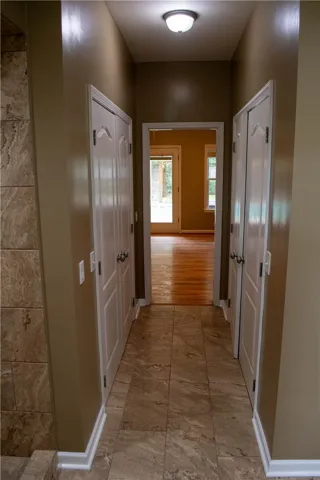 An inviting hallway with tiled flooring leads to rooms featuring warm hardwood floors and natural light.