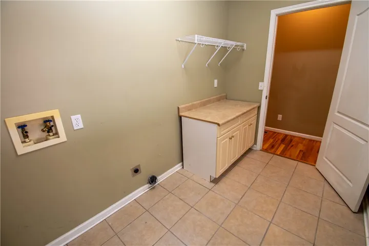Functional laundry room featuring a convenient countertop and upper shelving for organization.