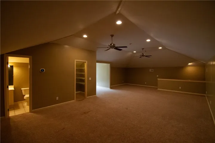 A spacious attic retreat features vaulted ceilings with recessed lighting and ceiling fans, perfect for flexible living.