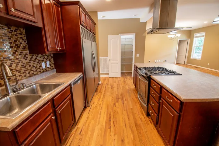 A well-appointed kitchen showcasing a central island, rich wood cabinetry, and gleaming stainless steel appliances.