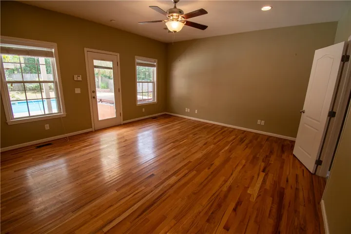 Hardwood floors reflect natural light from plentiful windows and glass doors leading to the exterior.