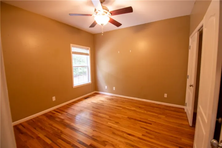 A comfortable bedroom features rich hardwood flooring and a functional ceiling fan for optimal comfort.