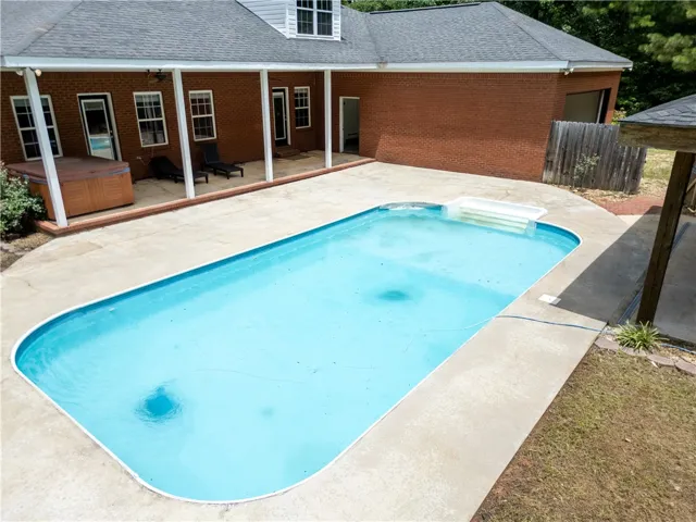 An inviting backyard oasis features a clear blue pool and a secluded hot tub, ideal for relaxation.