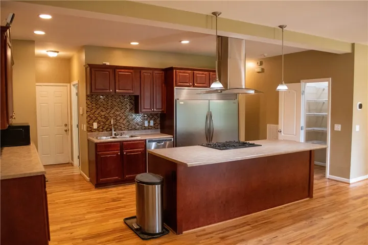 A chef's kitchen showcasing rich cabinetry and a central island with integrated cooktop.