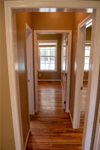 A warm hallway guides you through, revealing rich hardwood flooring.