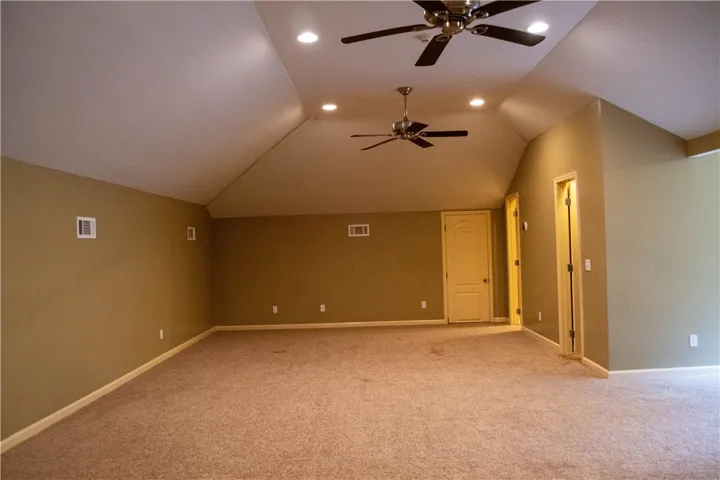A spacious room offers ample space, complete with multiple ceiling fans and recessed lighting.