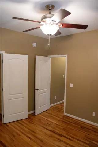 Rich hardwood flooring complements a functional ceiling fan with integrated lighting.
