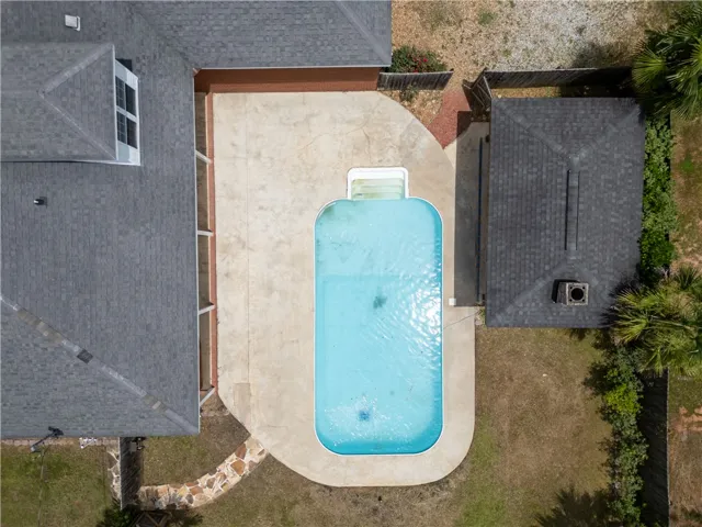 An aerial perspective reveals a sparkling pool nestled between structures and lush greenery.