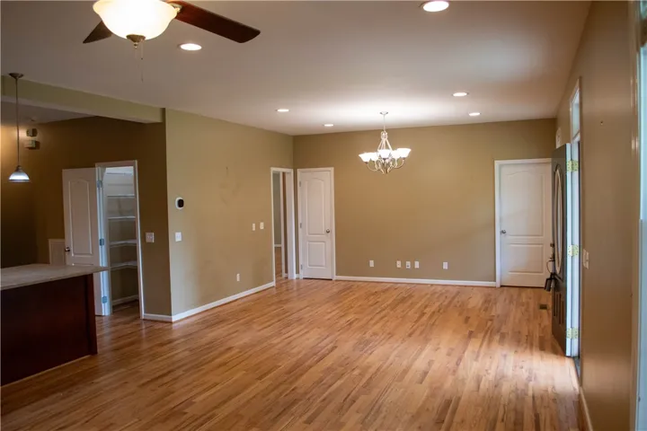 Golden hardwood flooring flows through this ample living space, illuminated by recessed lighting and a classic chandelier.