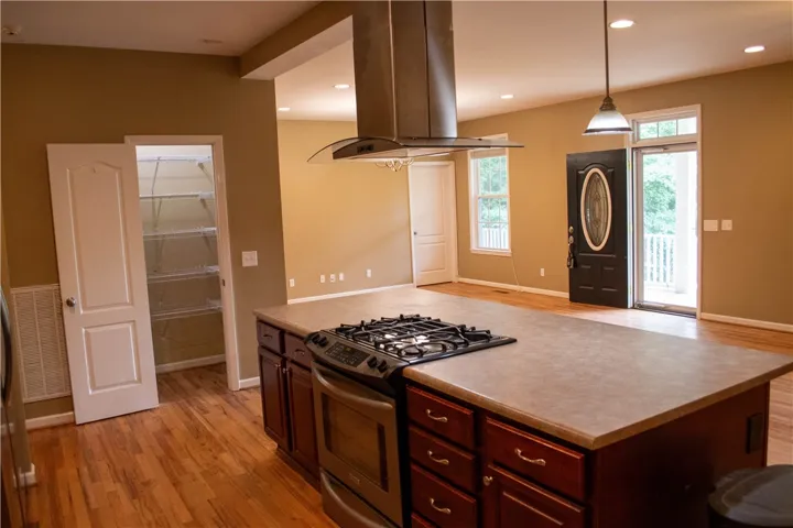 An open-concept living space highlights rich wood flooring and a modern kitchen island with integrated cooktop.