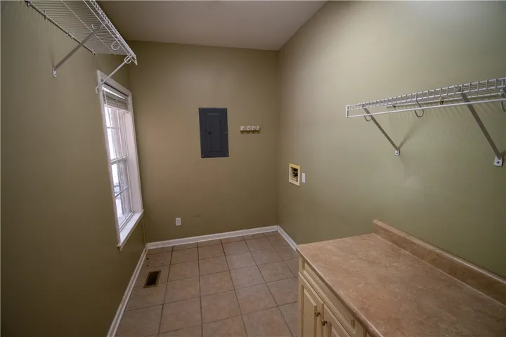 Functional laundry room featuring ample counter space and storage shelving.