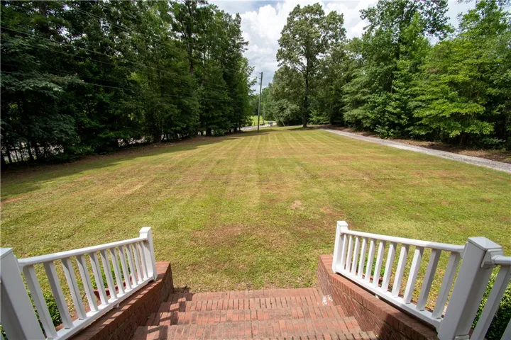 A spacious, verdant front lawn stretches invitingly toward a tree-lined perimeter.