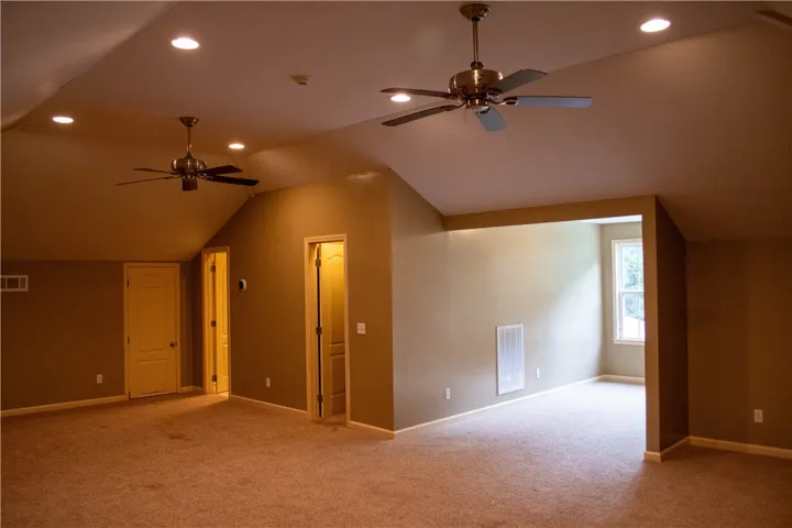 An inviting bonus room featuring vaulted ceilings and recessed lighting, ready for customization.
