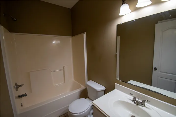 A well-lit bathroom features a functional shower-tub combination and a practical vanity.