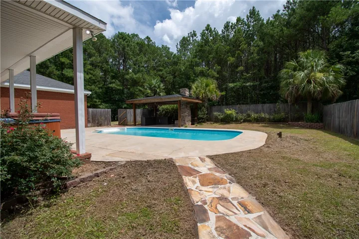 An inviting backyard oasis offers a sparkling pool and a charming outdoor kitchen pavilion.