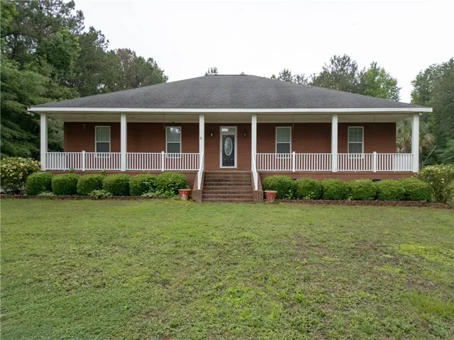 A classic brick facade welcomes guests with a charming covered porch and verdant lawn.