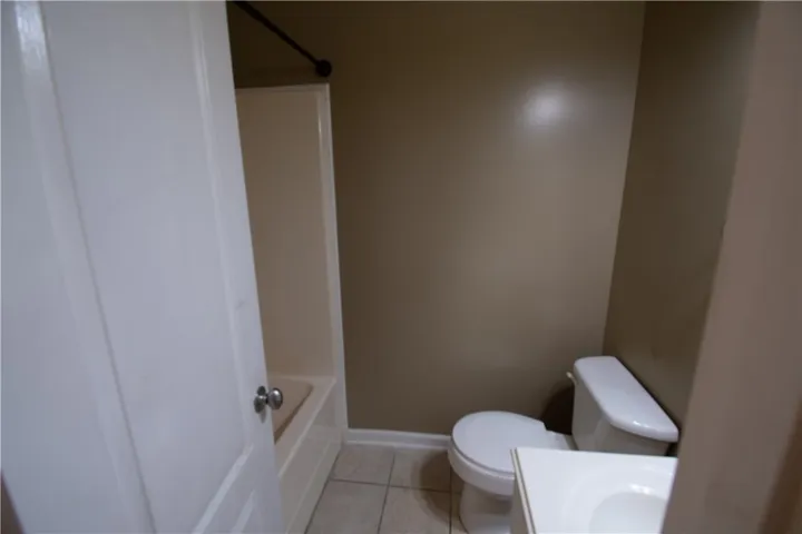 A well-maintained bathroom with a tub, toilet, and simple white vanity.