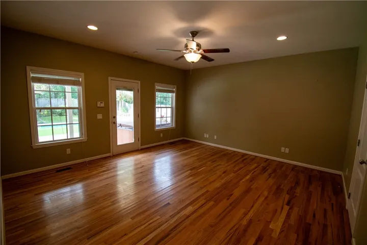 Natural light illuminates a room showcasing lustrous hardwood floors and convenient outdoor access.