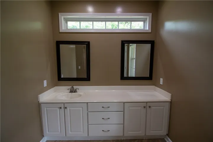 Double vanities with crisp white countertops provide ample space in this practical bathroom.