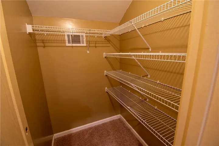 Ample wire shelving maximizes storage in this organized, carpeted walk-in closet.