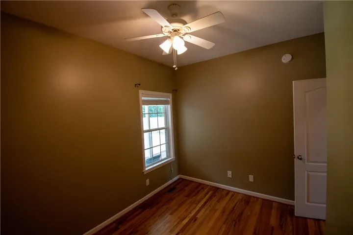 Hardwood floors and a bright window elevate this comfortable bedroom.