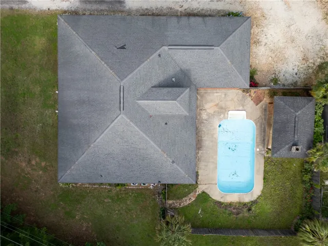 An aerial perspective reveals the property's inviting pool, nestled amidst mature greenery and an additional outbuilding.