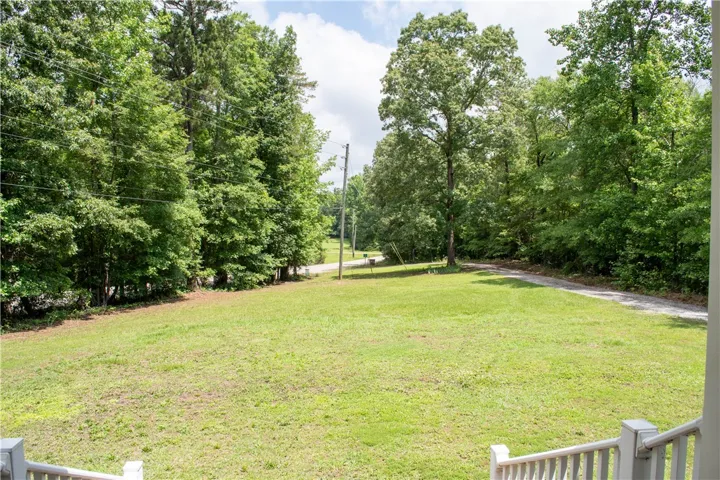 A verdant, open lot with mature trees and a long, winding driveway awaits your dream home.