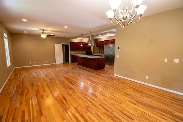 A vibrant chandelier illuminates the open-concept living space with polished hardwood flooring and a stylish kitchen.