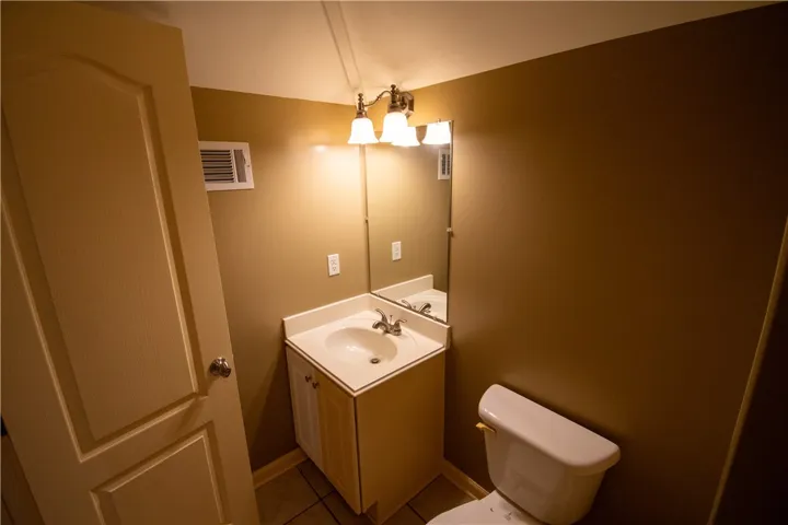 A well-lit powder room offers a simple vanity, mirror, and toilet, maximizing function in a compact footprint.