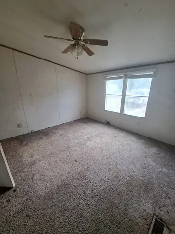 A well-proportioned bedroom offers carpeted flooring and an overhead ceiling fan.