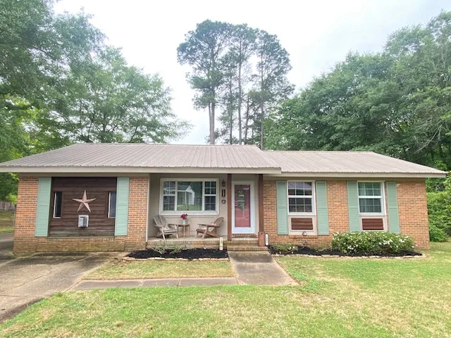 A charming single-story residence with a metal roof offers a welcoming curb appeal.