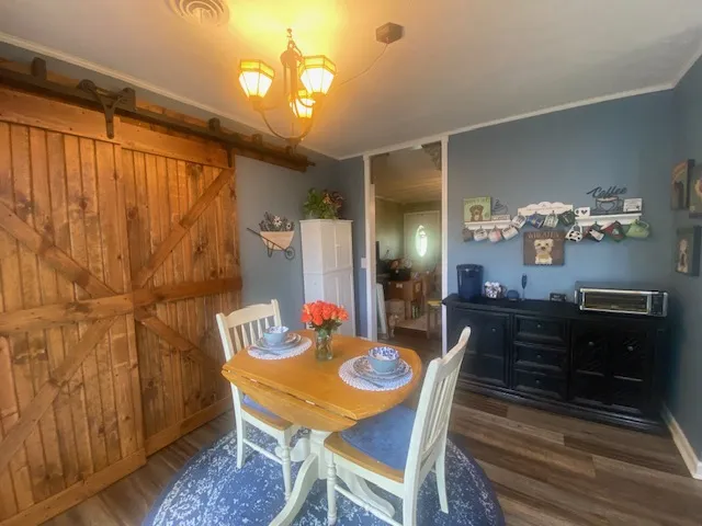 A charming dining area features a warm wooden barn door and elegant chandelier.