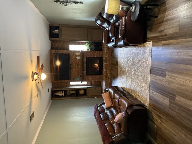 A well-lit gathering space features a stone fireplace and warm wood flooring.