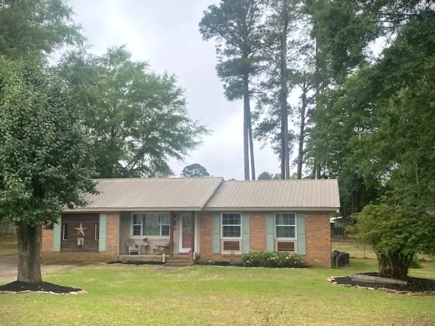 A charming brick dwelling framed by mature trees, offering a private, verdant setting.