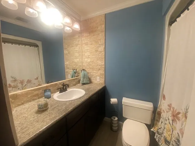 A compact bath features a single vanity, a well-lit mirror, and stone accents for a refined touch.