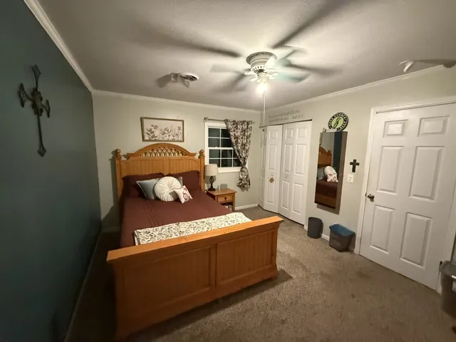 A comfortable bedroom with ceiling fan and carpeted floor provides a peaceful retreat.