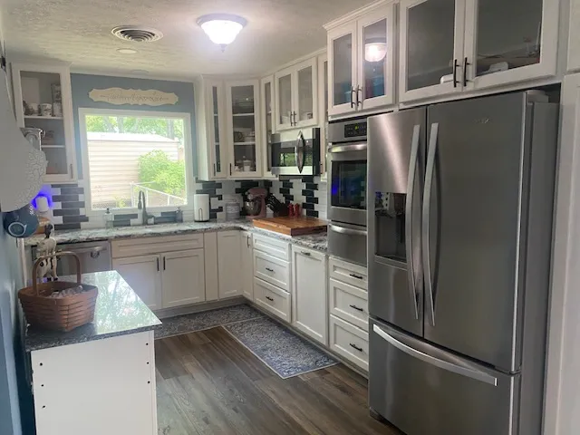 A contemporary kitchen showcasing stainless steel appliances, pristine white cabinetry, and durable granite counters.