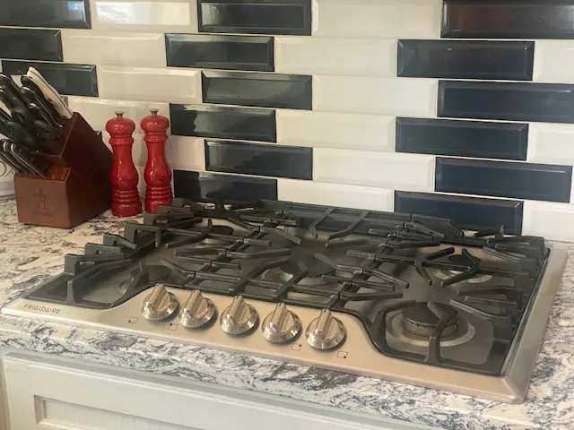 A sleek gas cooktop with modern controls integrates seamlessly into the granite countertop.