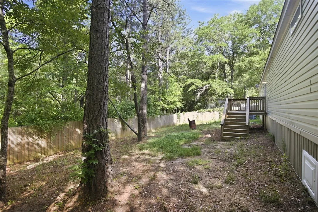 A tranquil yard with mature trees and a wooden privacy fence, offering a secluded retreat.