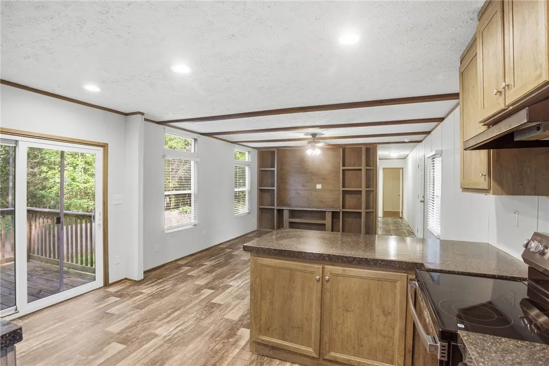 This airy open-concept living space features warm wood-look flooring and built-in shelving, seamlessly connecting to a private deck.