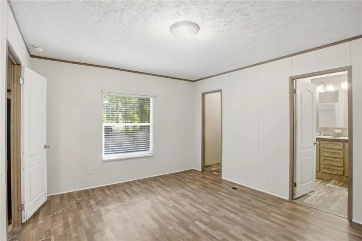 A well-lit room showcasing sturdy wood-look flooring and a peek into a well-appointed bathroom.