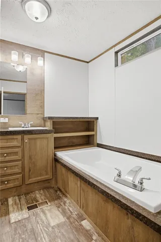 A deep soaking tub and vanity with ample storage create a functional and inviting bathroom retreat.