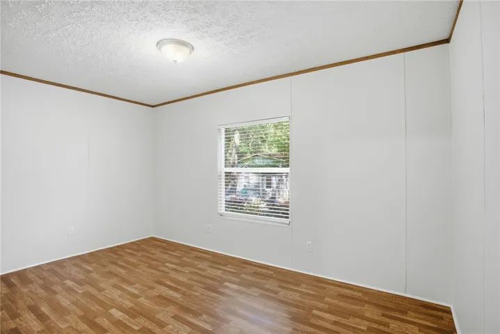 A well-lit room showcasing rich wood flooring and natural light through the window.