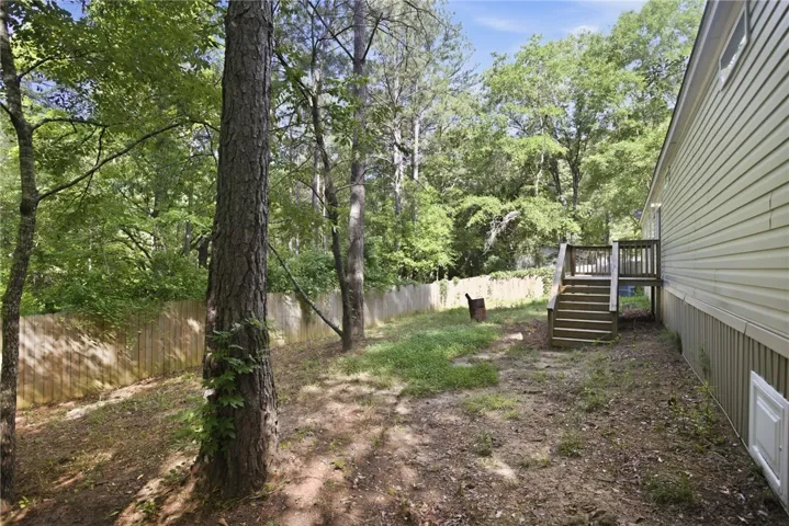 A tranquil yard with mature trees and a wooden privacy fence, offering a secluded retreat.