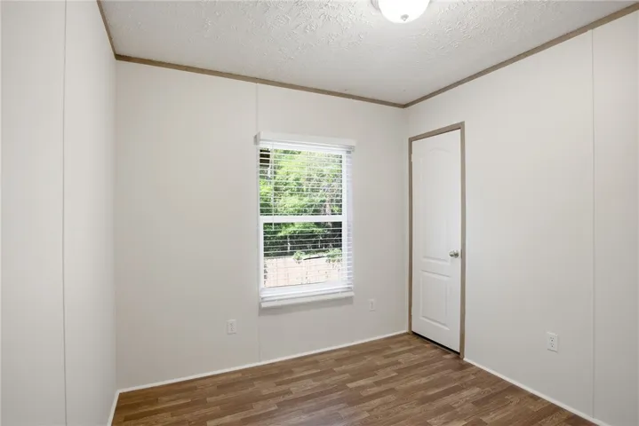 A quiet bedroom offering simple wood flooring and a large window for natural light.