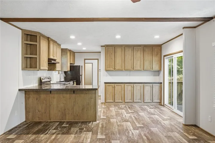 A well-lit kitchen with ample cabinetry and rich wooden floors offers seamless indoor-outdoor access through sliding doors.