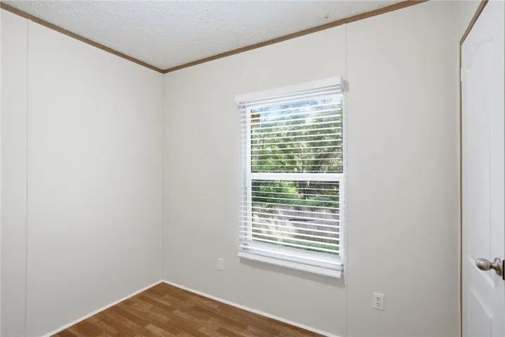 A well-lit room showcasing rich wood flooring and a refreshing outdoor vista through the window.