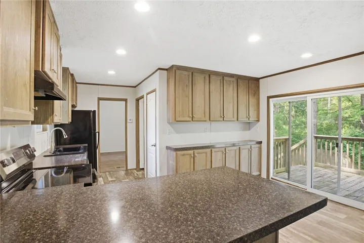 A functional kitchen with plentiful cabinetry, durable countertops, and convenient deck access for outdoor living.